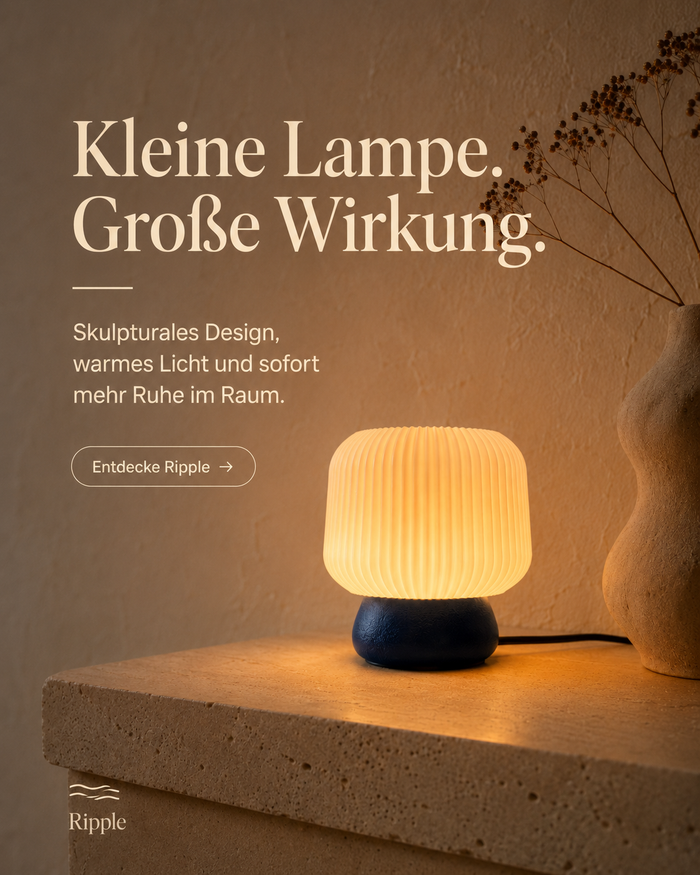 Ripple Tischleuchte in Indigo auf einer Steinablage neben einer Vase, eingeschaltet – Instagram-Grafik „Kleine Lampe. Große Wirkung.“