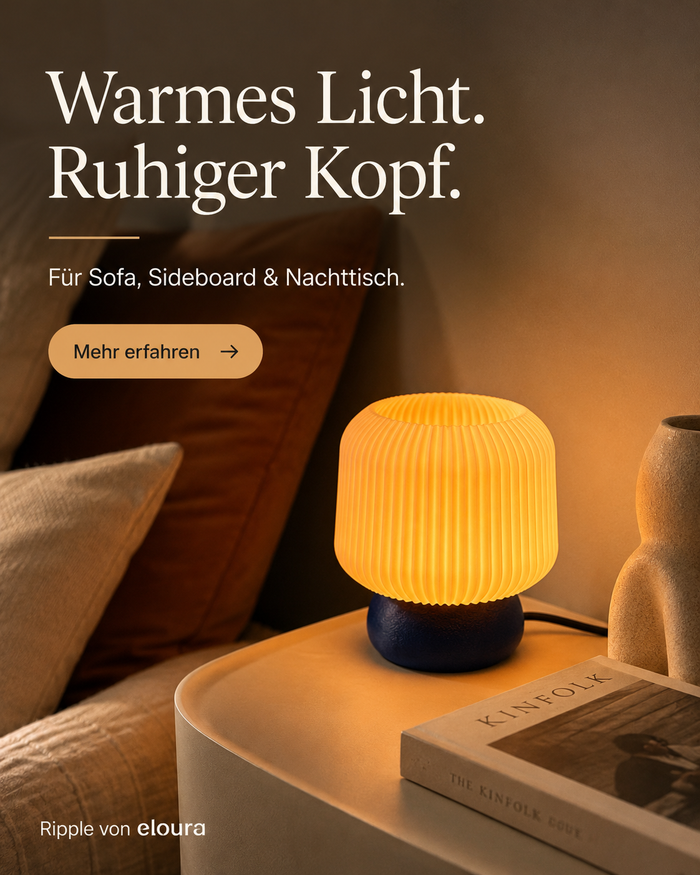 Ripple Tischleuchte in Indigo auf einem Beistelltisch neben einem Sofa, eingeschaltet mit warmem Licht – Instagram-Grafik „Warmes Licht. Ruhiger Kopf.“